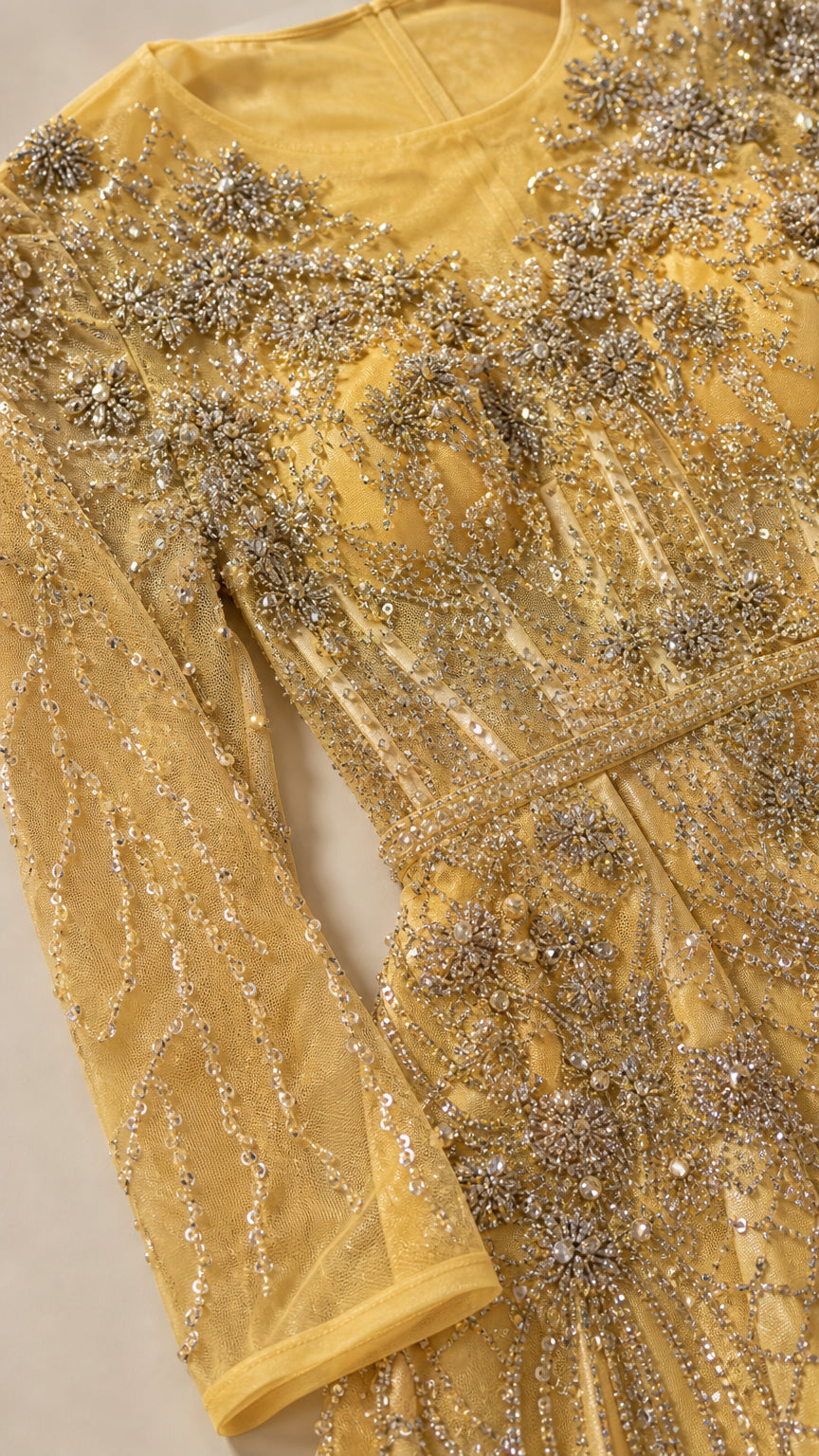 Close-up detail of yellow gold sheer mesh fabric with intricate beadwork and crystal embroidery