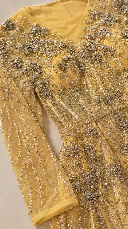Close-up detail of yellow gold sheer mesh fabric with intricate beadwork and crystal embroidery
