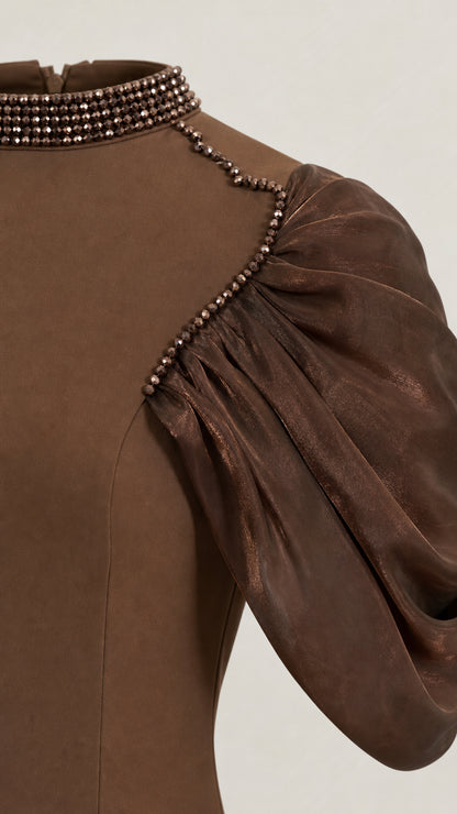Close-up detail of beaded mock collar and pleated puff sleeve attachment on brown dress