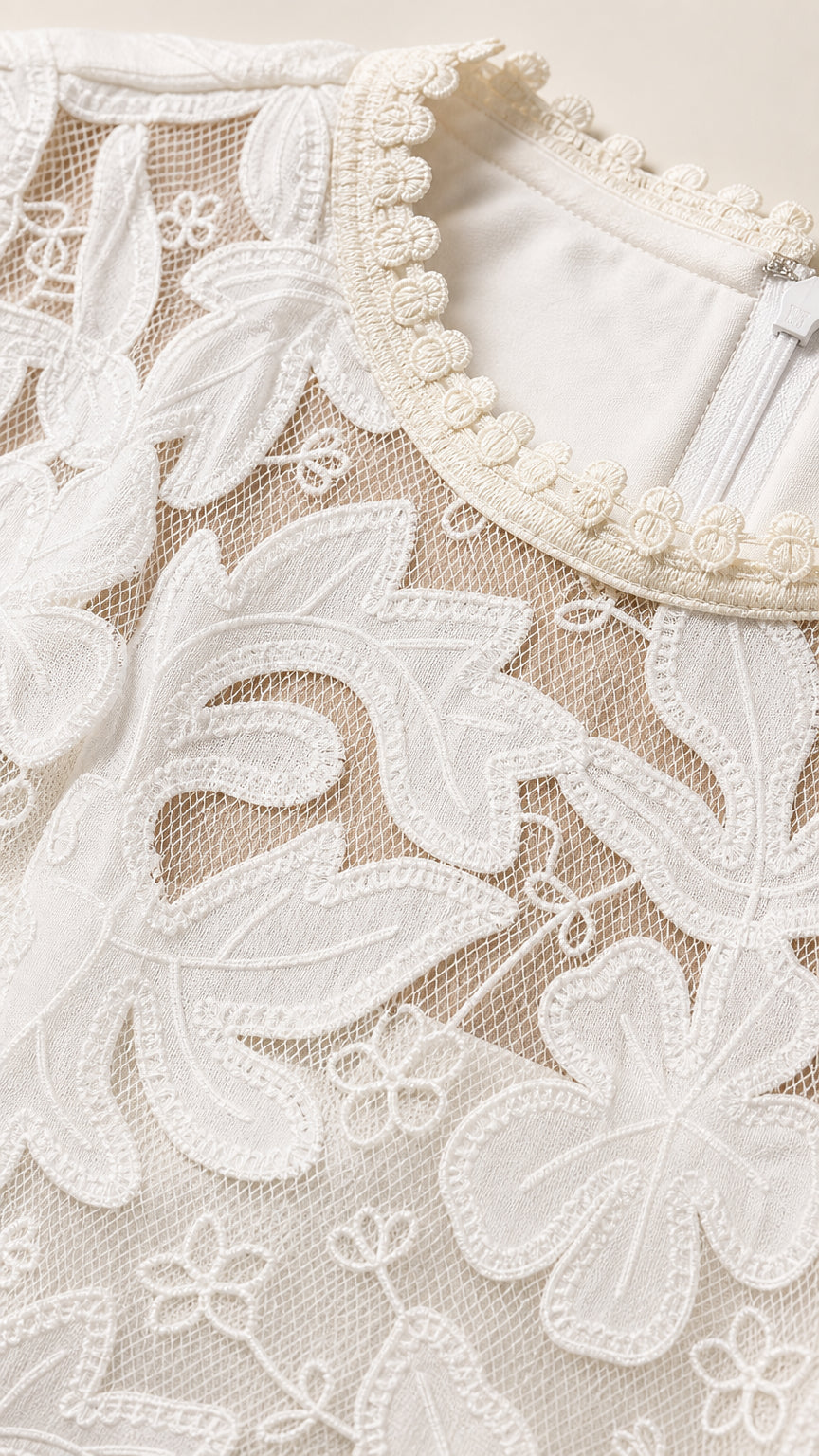 Close-up detail of white floral embroidery and beaded pearl-like trim along the neckline