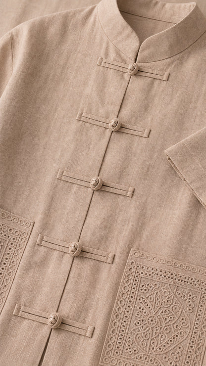 Close-up of taupe mandarin collar, knot frog buttons, and embroidered patch pocket