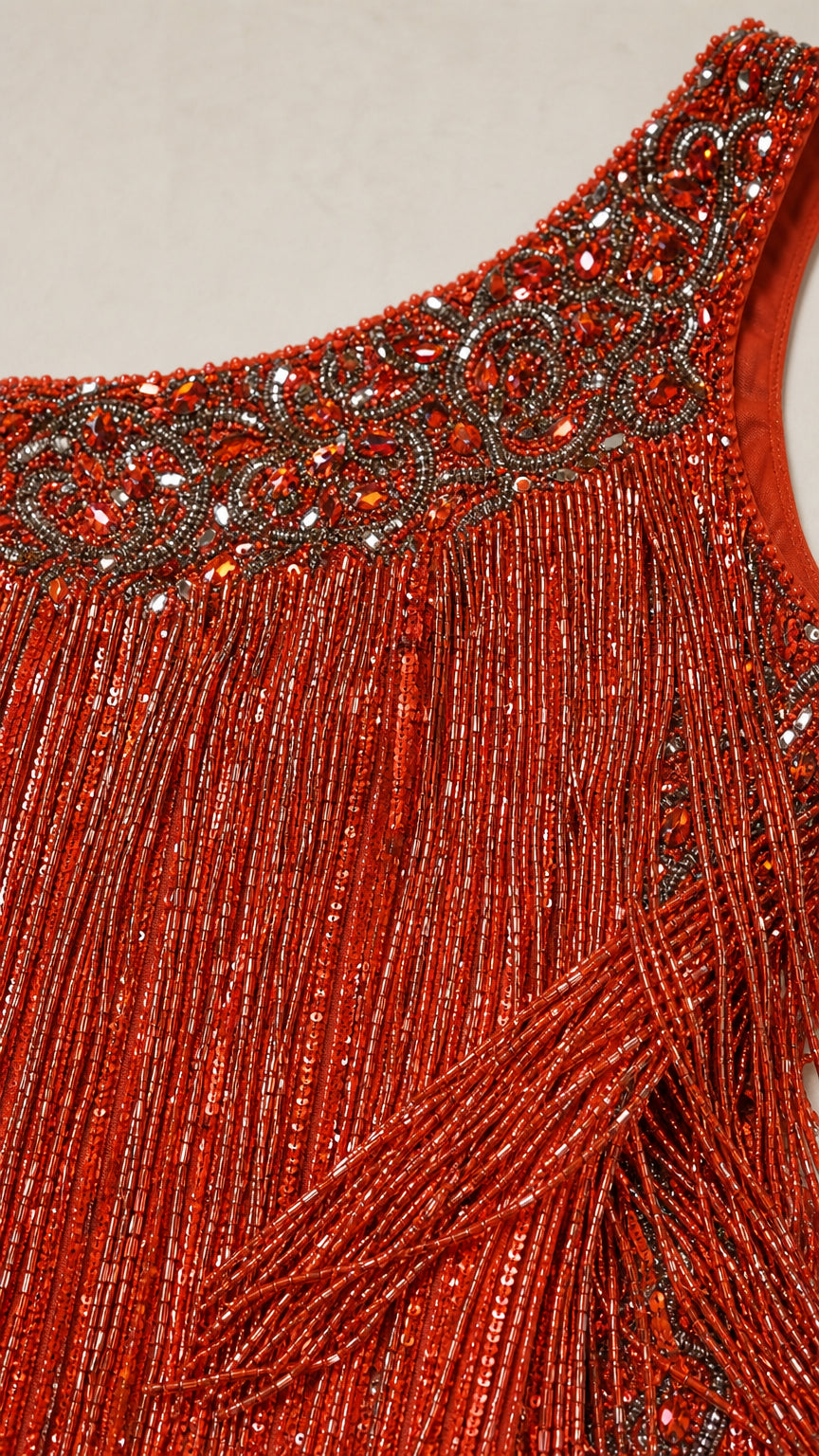Close-up detail of embellished beaded neckline and red-orange tassel fringe