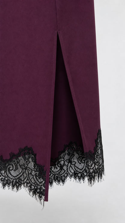 Close up view of scalloped black eyelash lace trim and side slit on dress hem