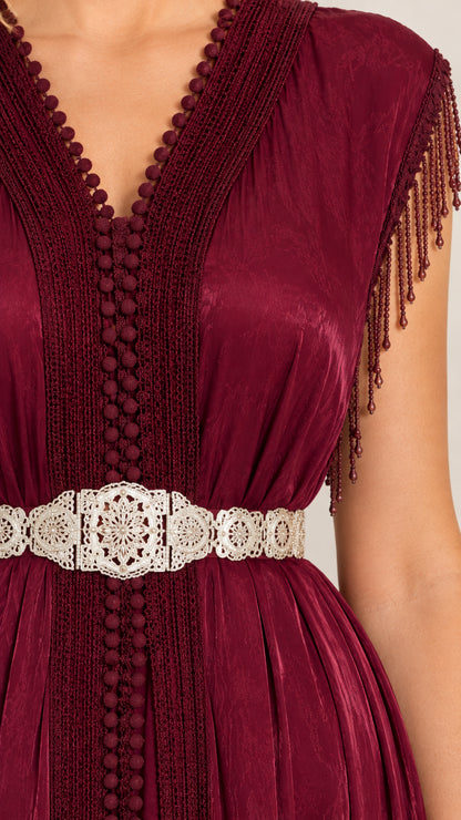 Close up view of burgundy dress bodice with textured neckline trim and filigree belt