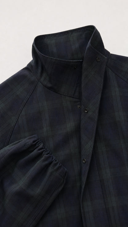 Close-up detail of the snap-button high stand collar and sleeve cuff on dark plaid jacket