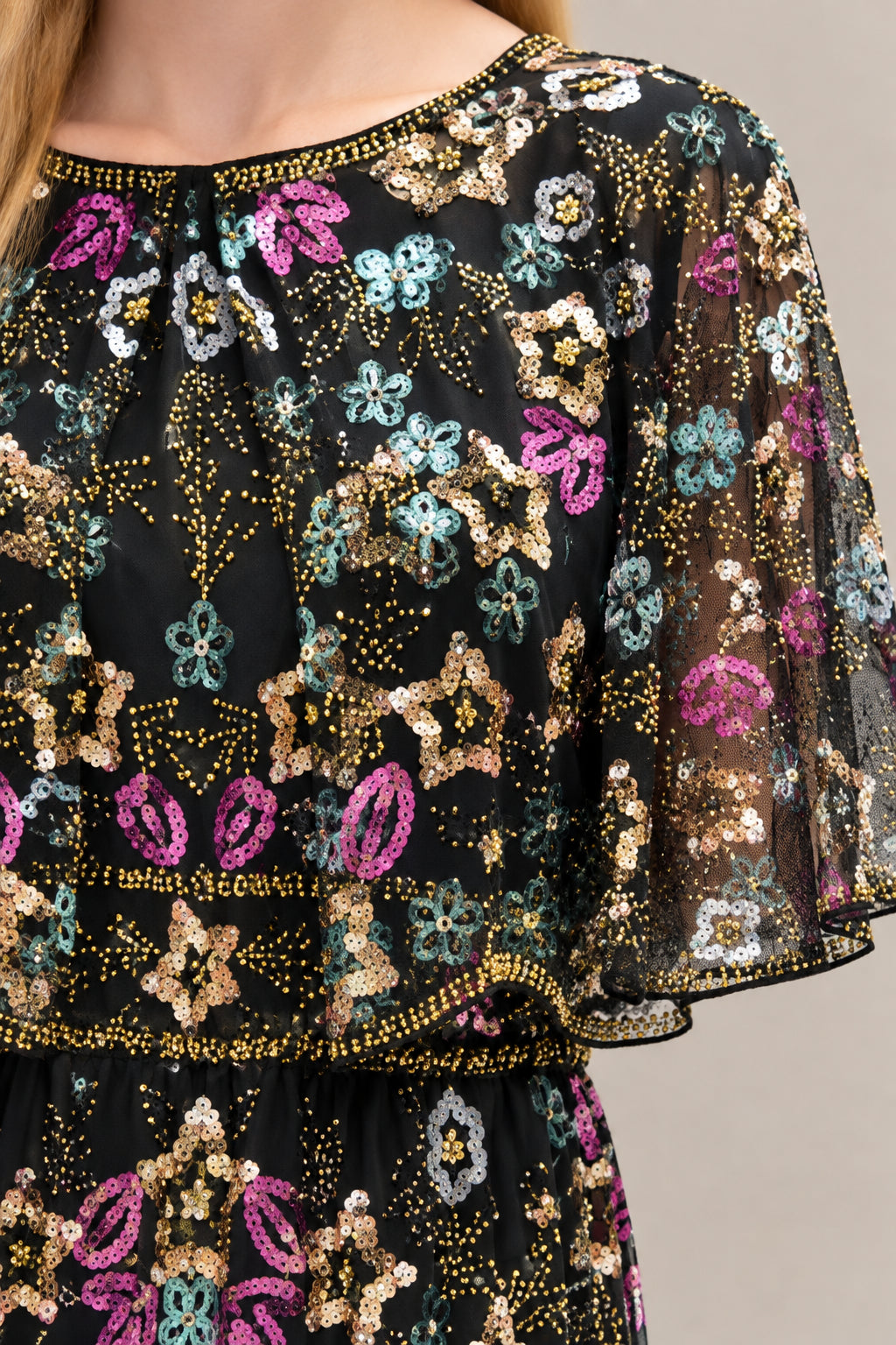 Close-up detail of multi-color floral sequin embroidery and capelet neckline