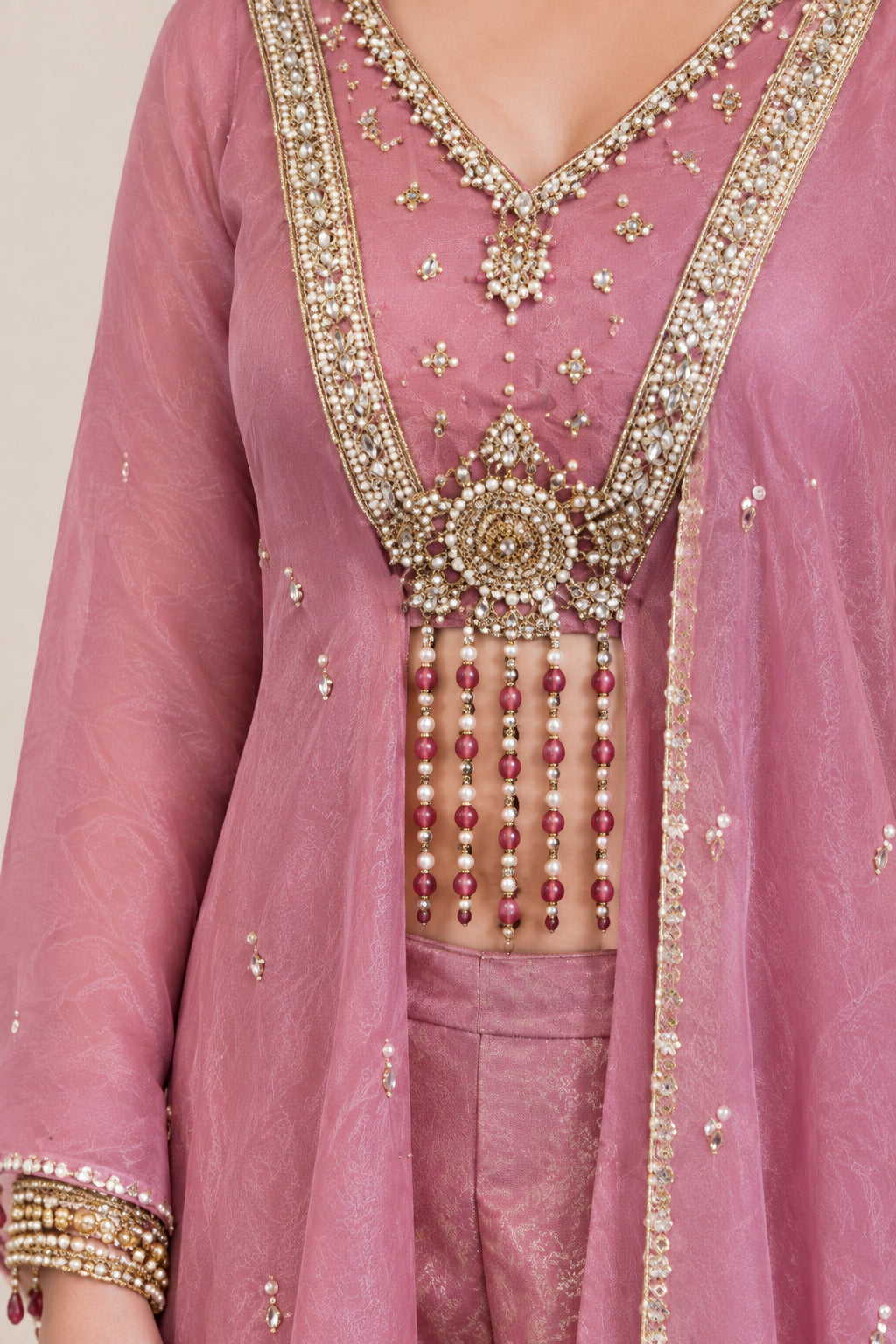 Close-up of intricate metallic embroidery and hanging bead fringe on Dusty Rose crop top