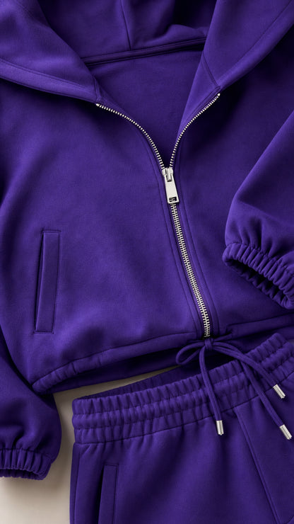 Close-up detail of purple zip-up hoodie zipper, pocket, and drawstring sweatpants waistband