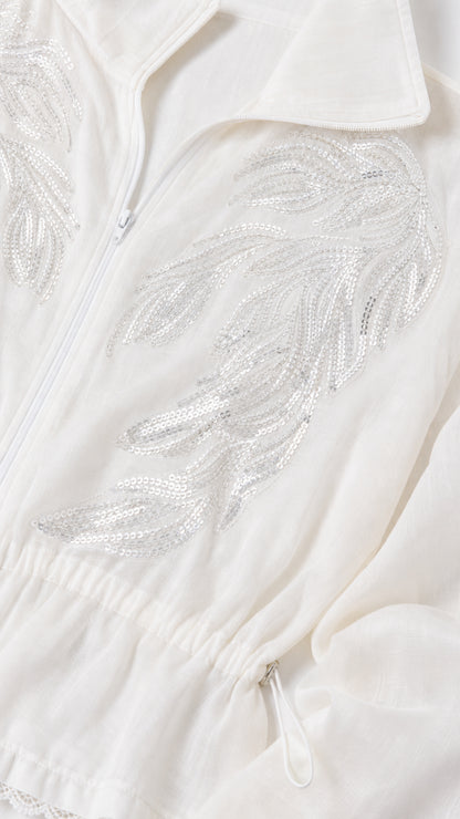 Close-up of intricate silver sequin leaf embroidery on white zip-up jacket
