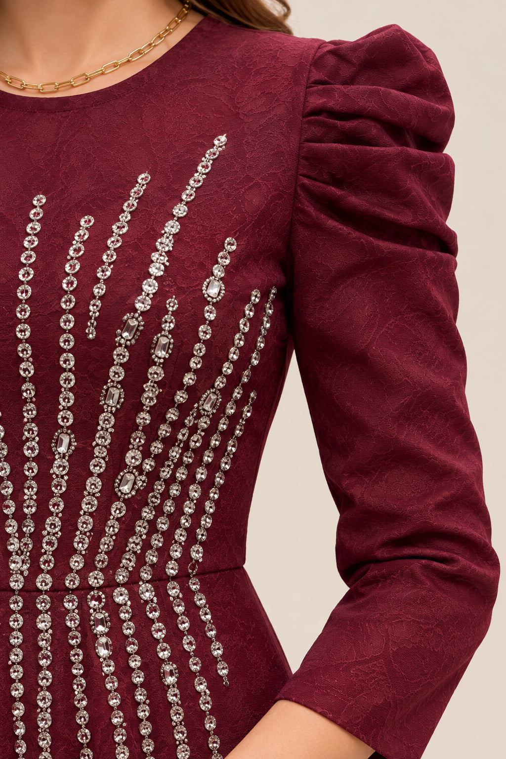 Close-up detail of rhinestone bodice embellishments and pleated puff shoulders on burgundy gown
