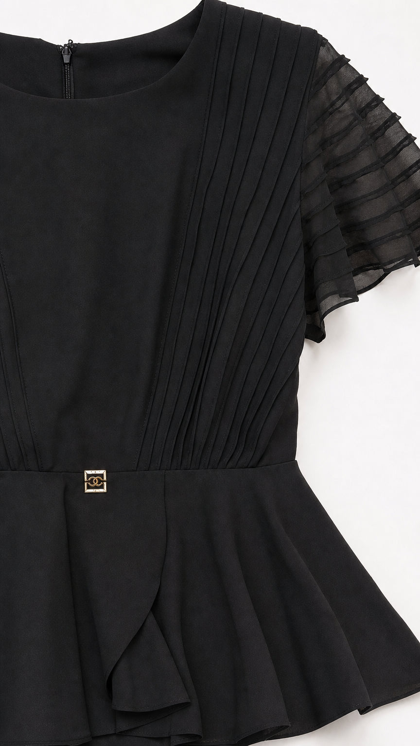 Close-up detail of pleated bodice and peplum accent on black dress
