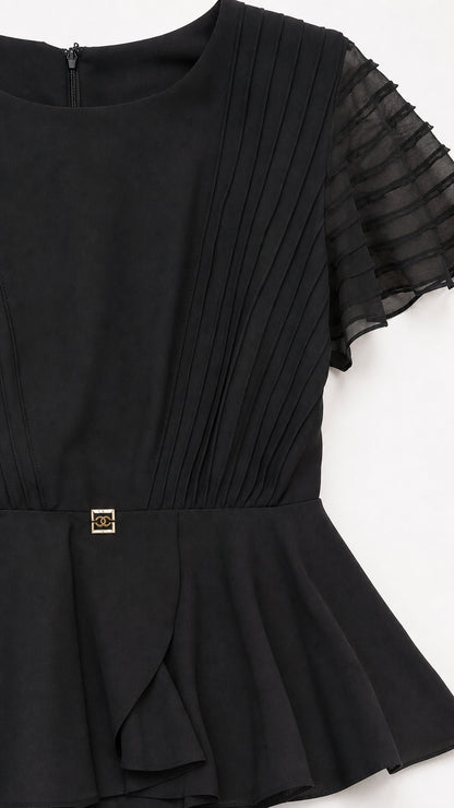 Close-up detail of pleated bodice and peplum accent on black dress