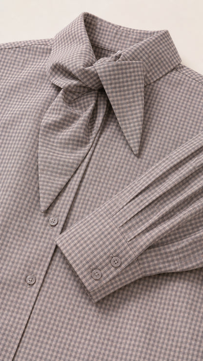 Close-up detail of grey houndstooth fabric, tie collar, buttons, and pleated cuff