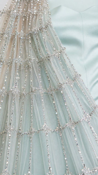 Close-up detail of geometric beadwork and sequins on the sheer mesh cape