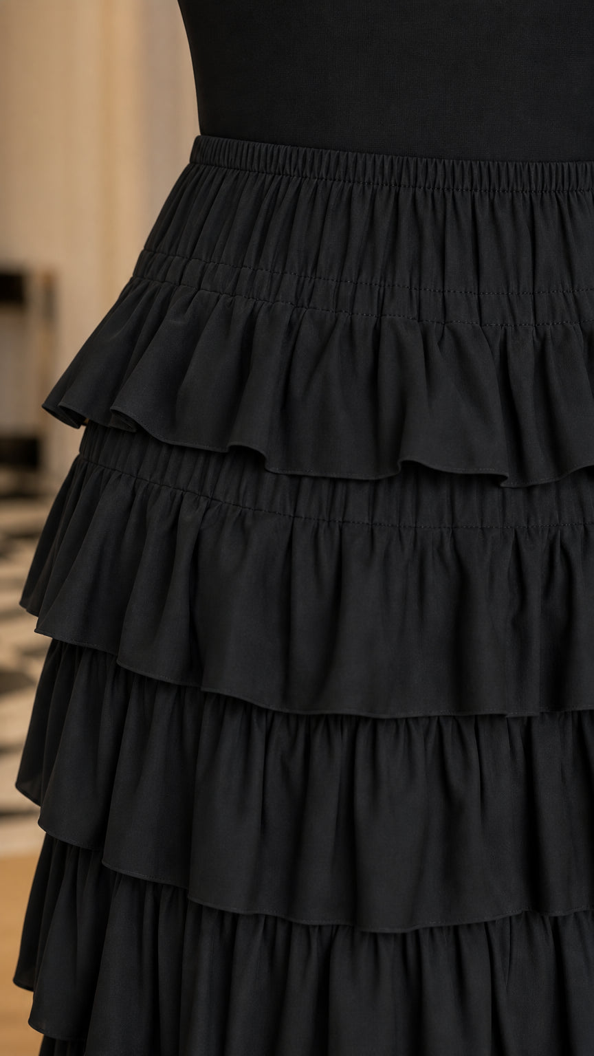 Close-up detail of the layered horizontal ruffles on the black maxi skirt