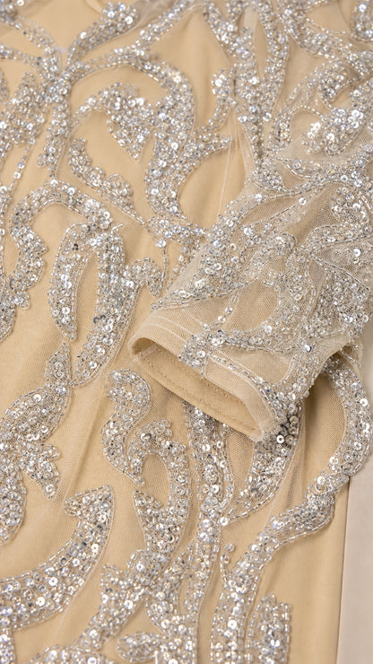 Close-up of intricate silver sequin scroll embroidery on sheer mesh fabric