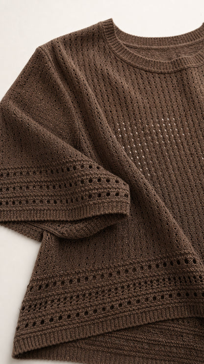 Close-up detail of brown textured pointelle openwork knit fabric and hem stitching