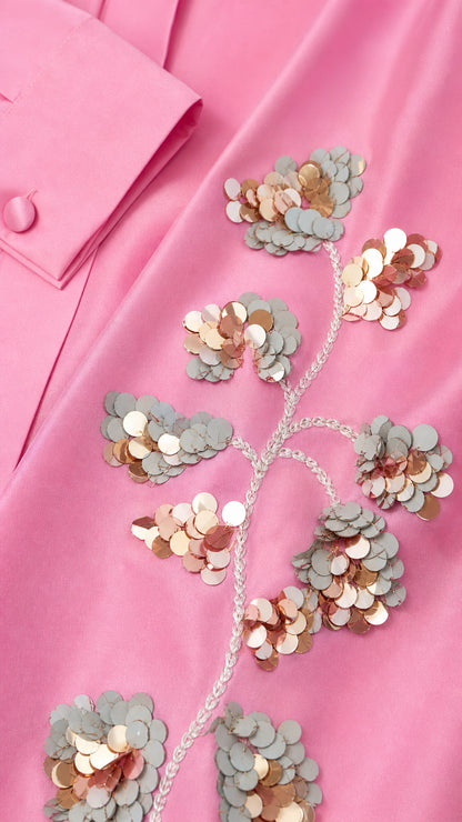 Close-up detail of shimmering floral sequin embroidery and buttoned cuff on pink fabric