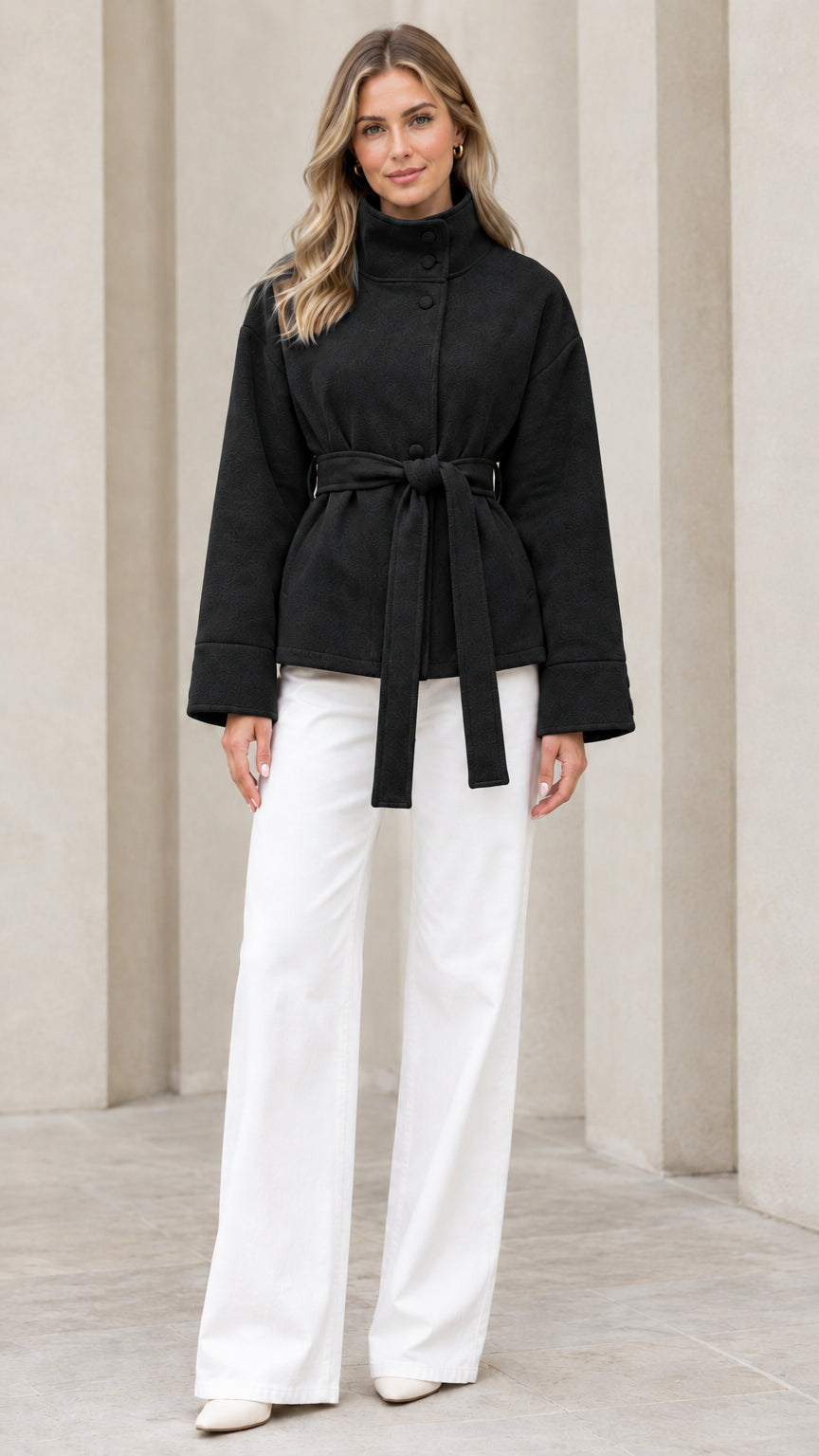 Front view of model wearing black stand collar belted jacket