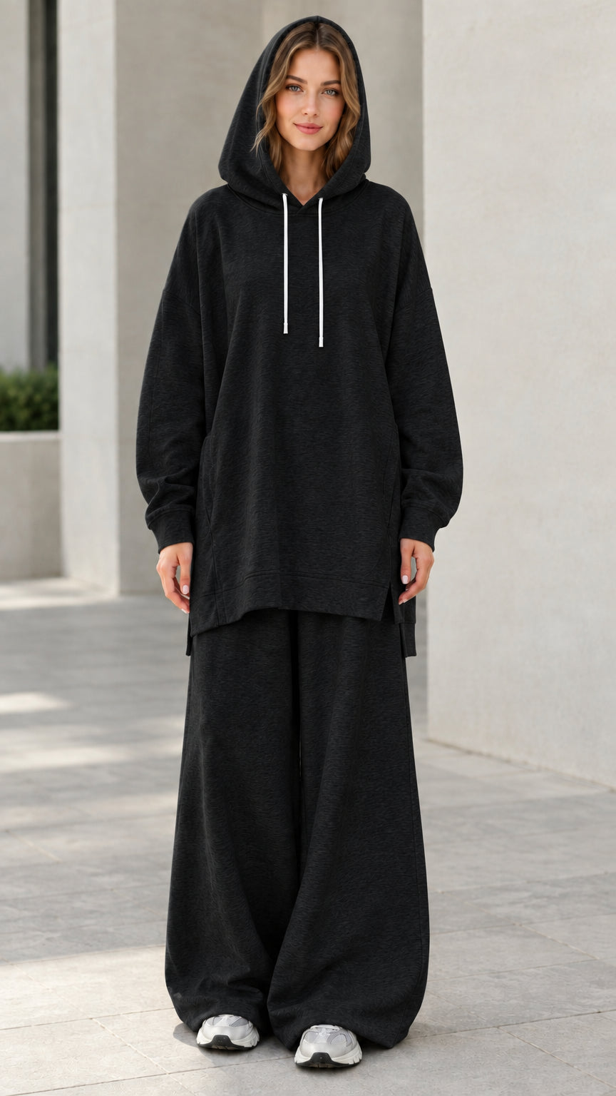 Woman wearing black oversized longline hoodie and matching wide-leg sweatpants lounge set