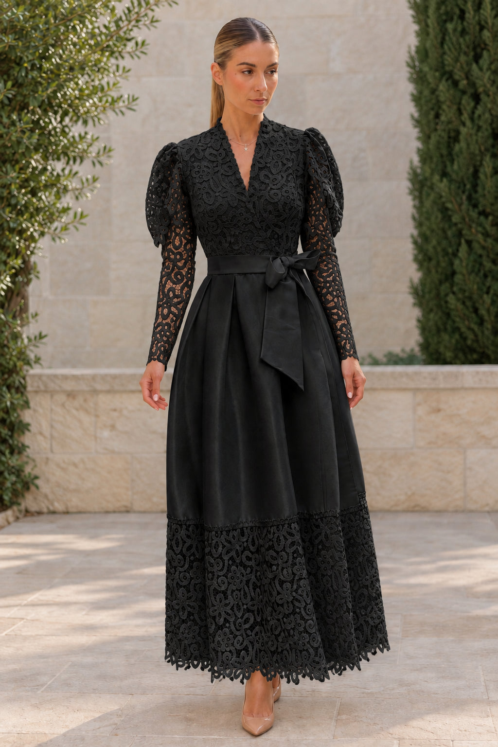 Woman wearing black floral lace puff long sleeve belted satin maxi dress
