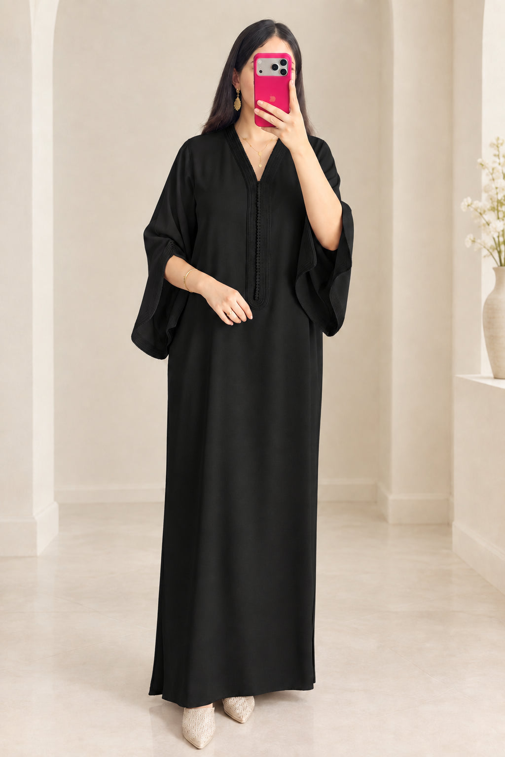Front view of woman wearing black kaftan maxi dress with embroidered V-neck