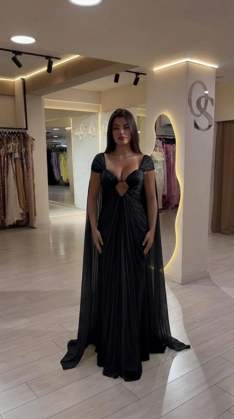 Front view of Black pleated sweetheart maxi gown with cape sleeves