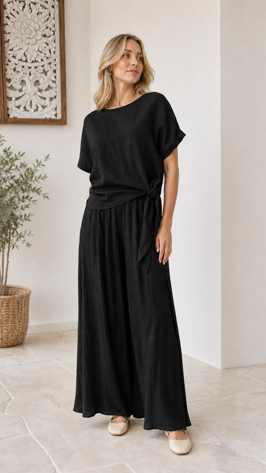 Model wearing classic black short-sleeve tie-waist top and wide-leg pants set