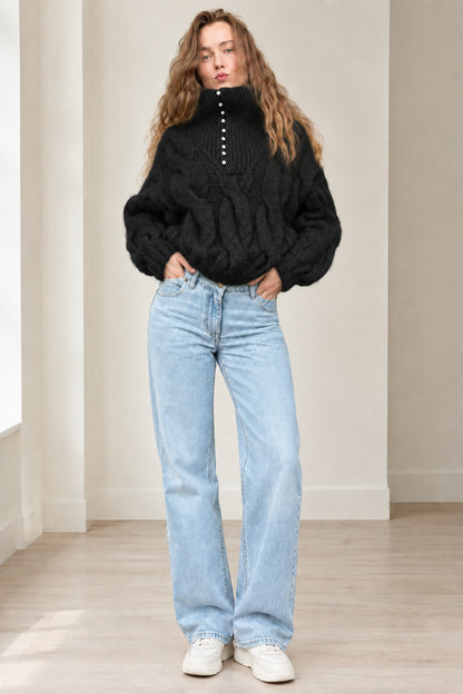 Model wearing black chunky cable knit button high neck sweater