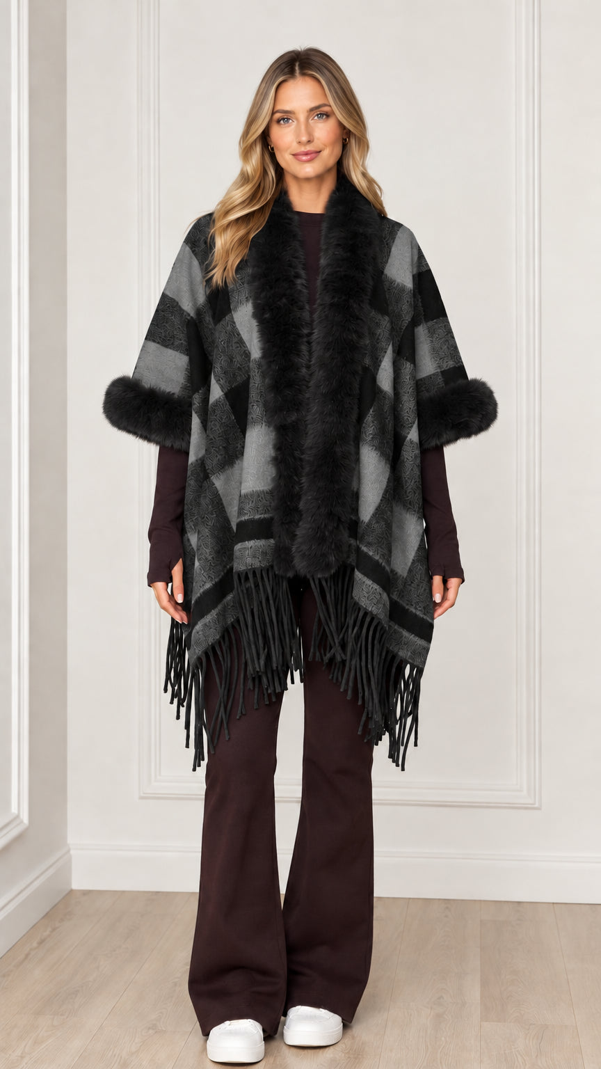 Woman wearing charcoal grey plaid poncho wrap with black faux fur trim