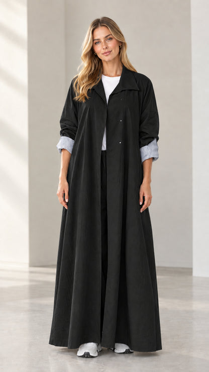 Full-length front view of woman wearing black maxi duster coat with striped cuffs
