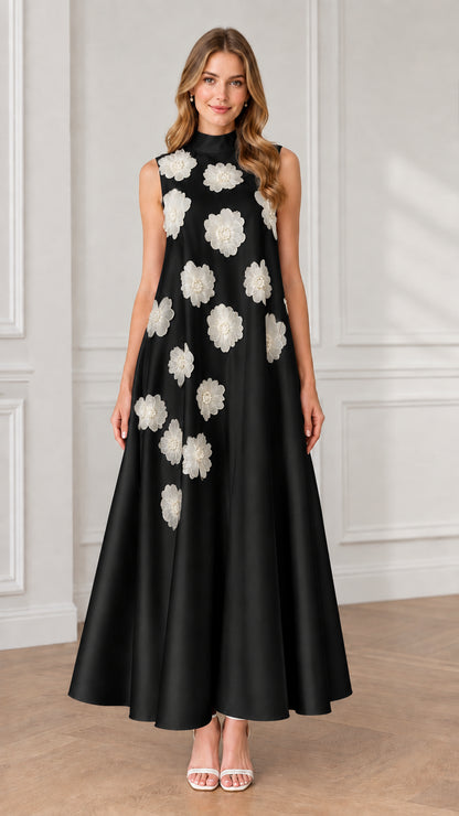 Model wearing black sleeveless high neck maxi dress with contrasting white floral appliqués