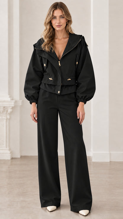 Front view of woman wearing black cropped hooded utility jacket with matching black pants