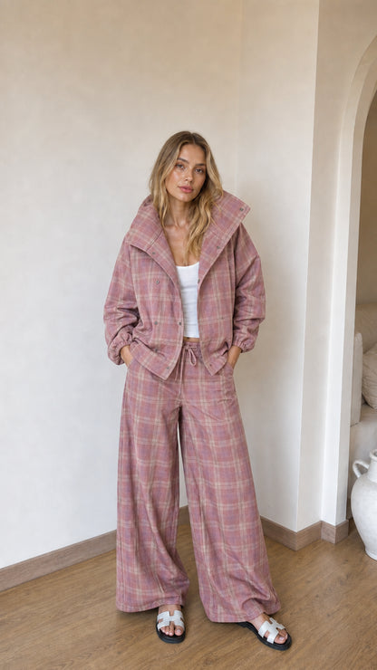 Model wearing dusty pink plaid high-collar jacket and matching wide-leg lounge pants