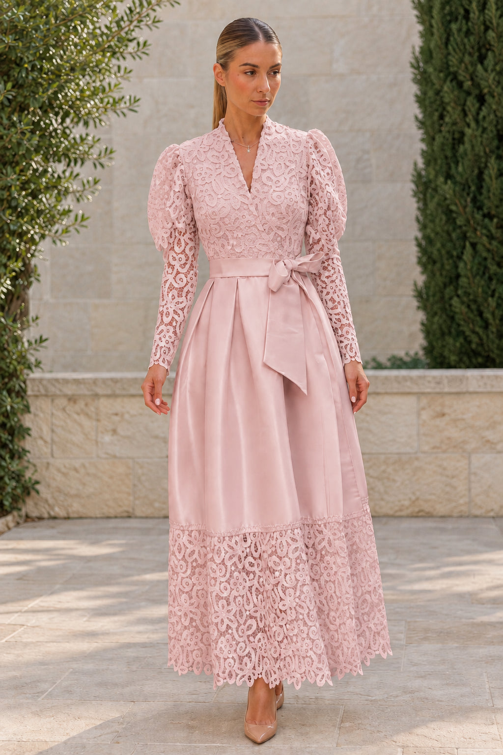 Woman wearing dusty pink lace bodice belted satin maxi dress with lace hem