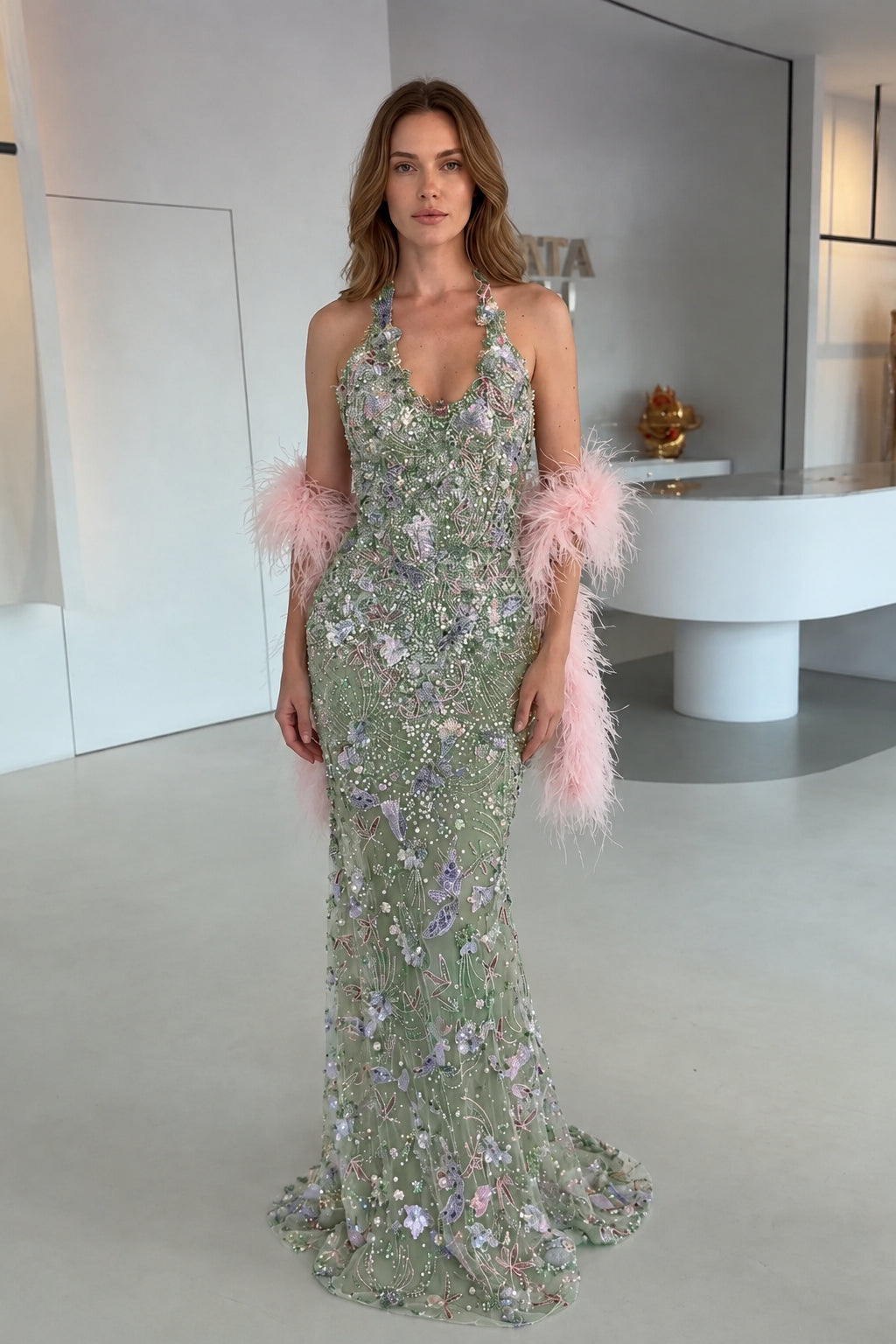 Model wearing Sage Green floral embellished halter evening gown with pink feather stole