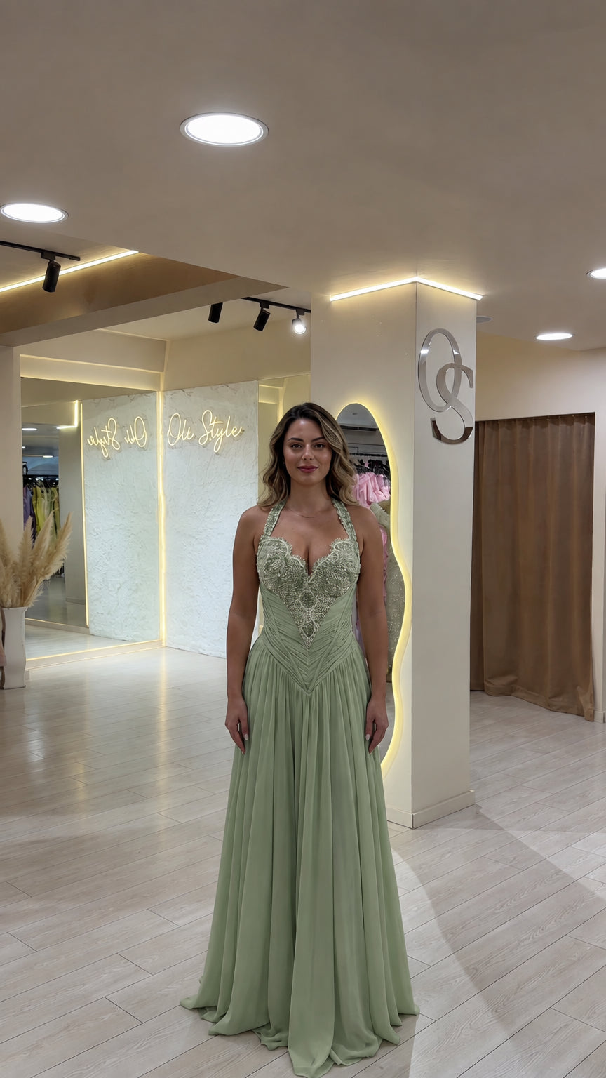 Model wearing sage green halter bodice evening gown with flowing skirt
