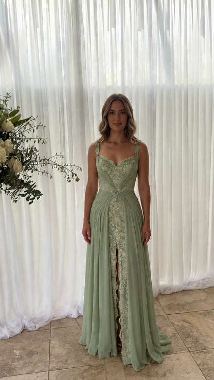 Front view of model wearing sage green pleated chiffon formal gown with lace slit