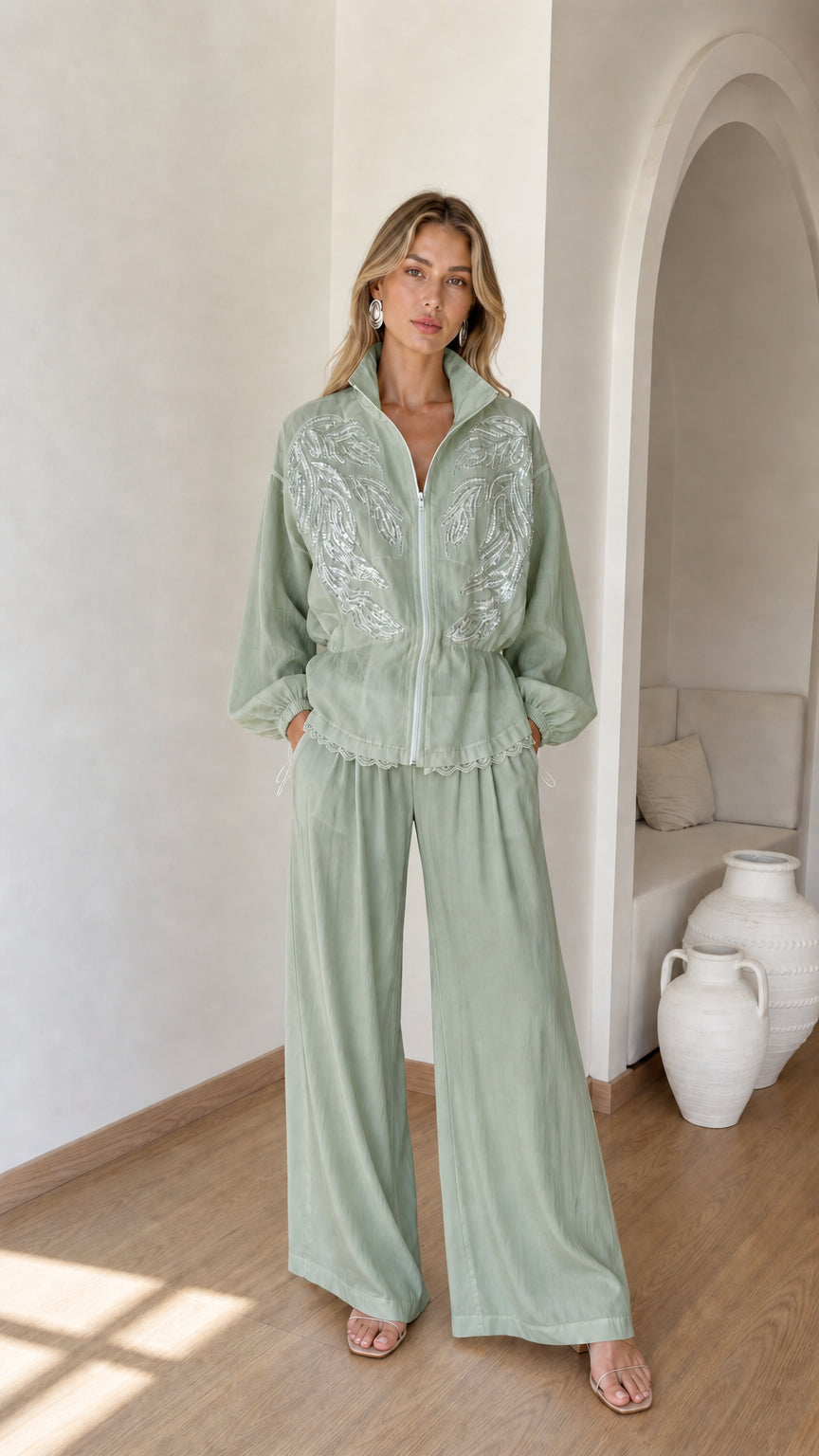 Front full view of woman wearing sage green embroidered zip jacket and wide-leg pants set