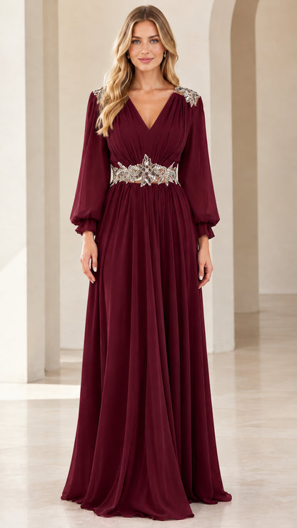Front view of woman wearing burgundy long-sleeve chiffon evening gown with crystal waistband