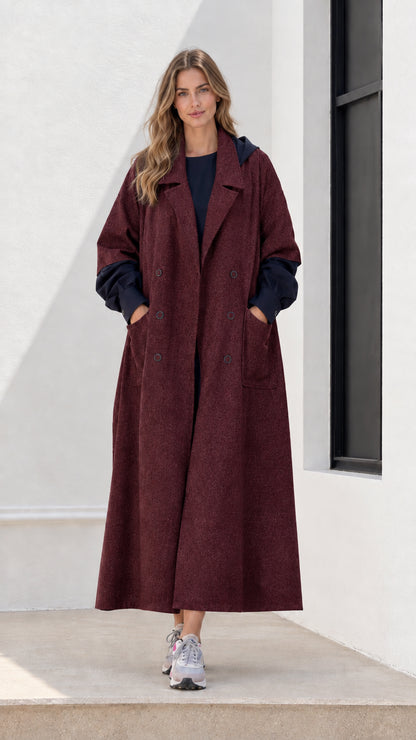 Full-length front view of woman wearing burgundy red hooded maxi trench coat