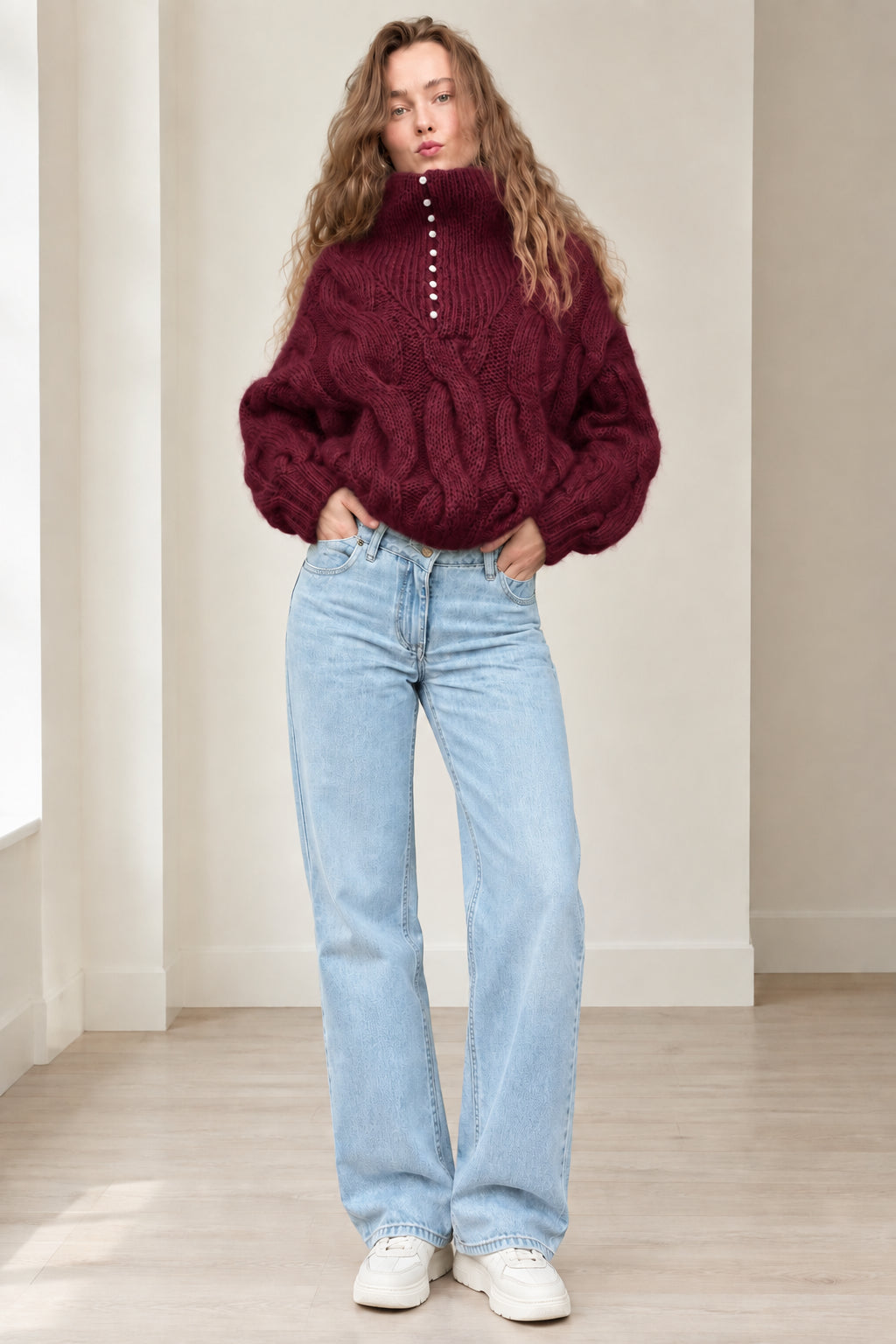 Model wearing burgundy red chunky cable knit button high neck sweater