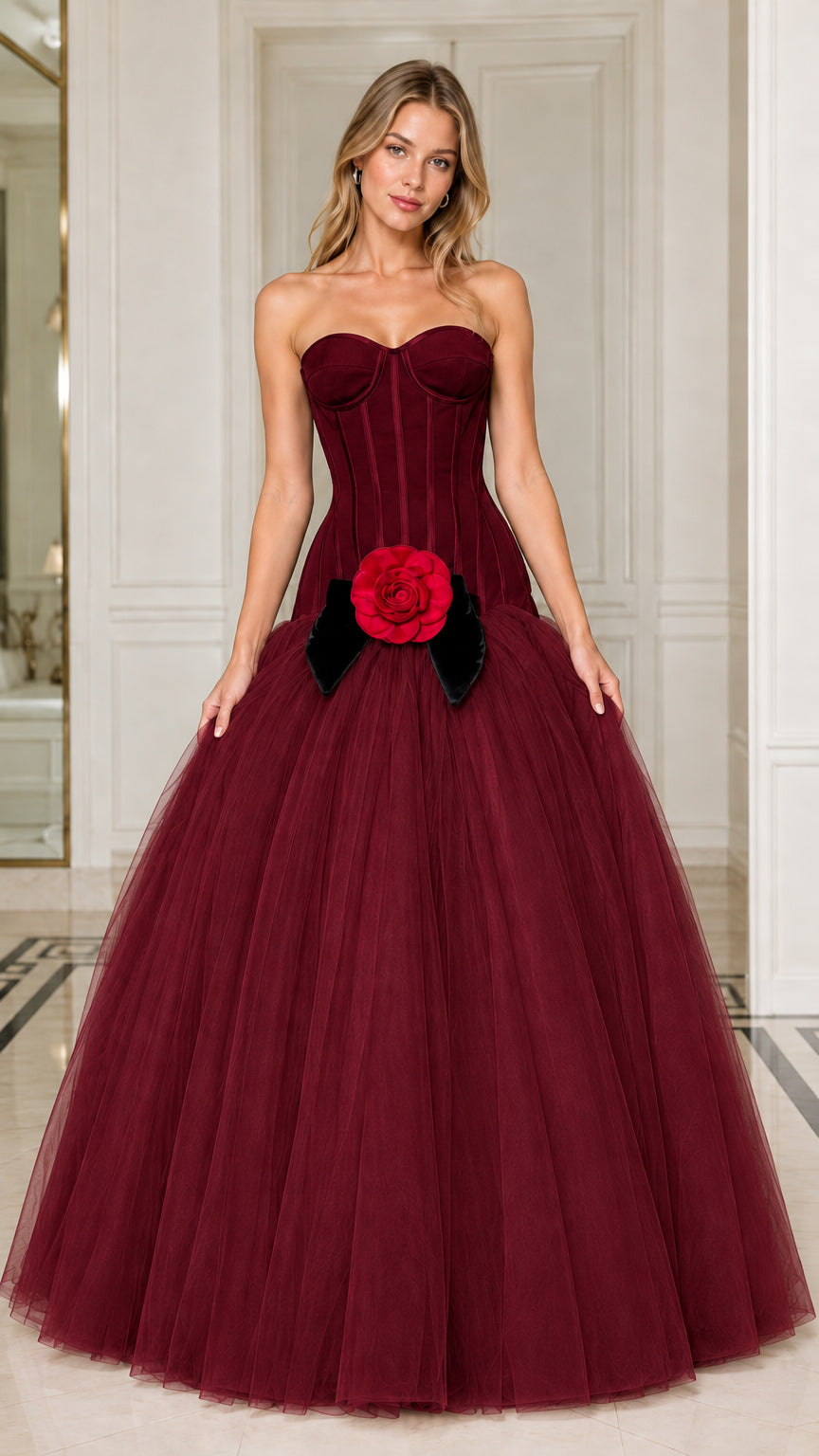 Model wearing rich burgundy strapless corset ball gown with red rose detail