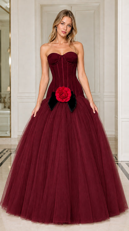 Model wearing rich burgundy strapless corset ball gown with red rose detail