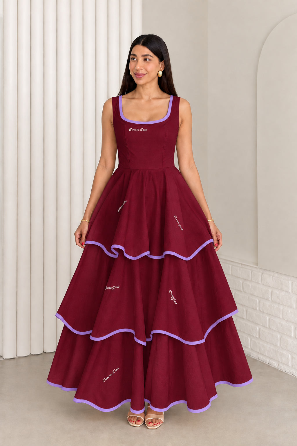 Model wearing burgundy sleeveless tiered maxi dress with purple contrast trim