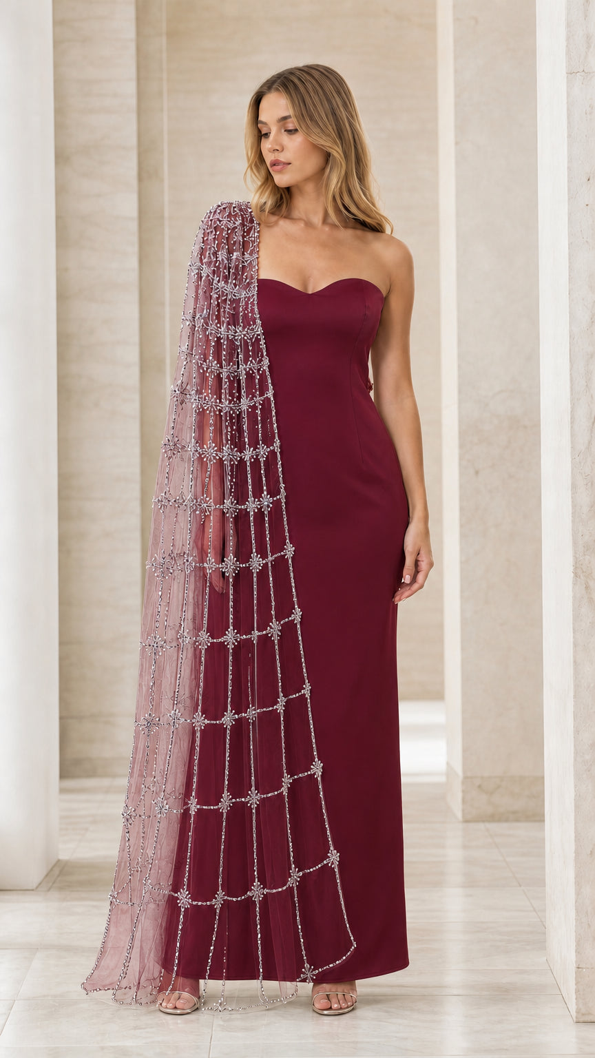 Model wearing rich burgundy strapless evening gown with beaded mesh cape