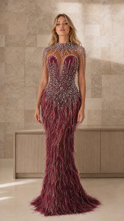 Front view of burgundy beaded illusion feather evening gown