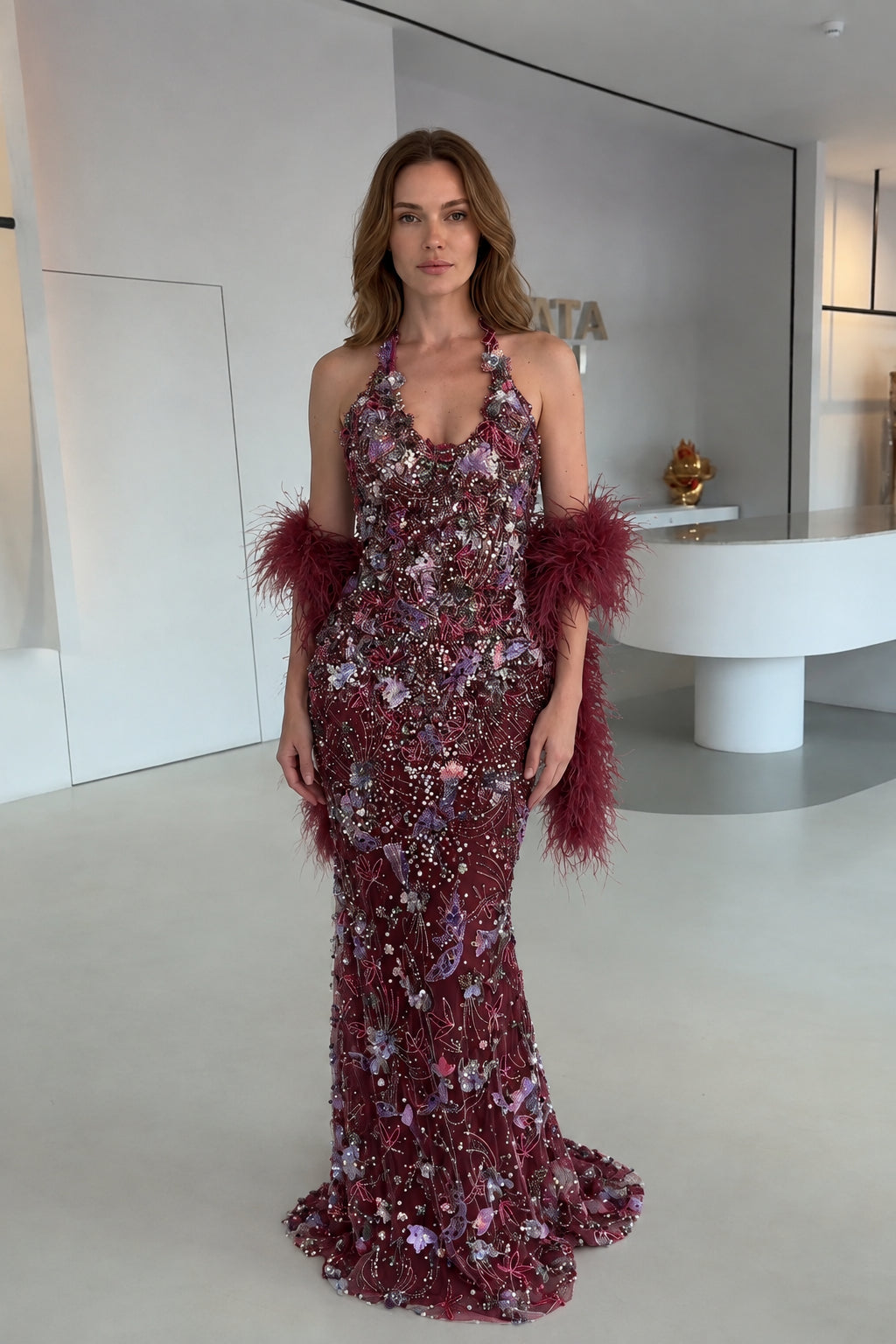 Model wearing Burgundy floral embellished halter evening gown with matching wine feather stole