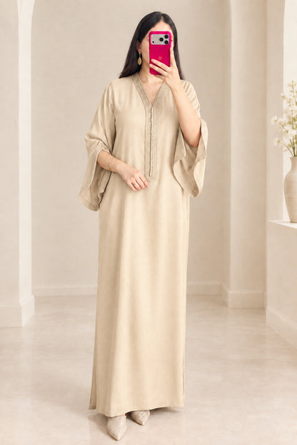 Front view of woman wearing beige kaftan maxi dress with embroidered details