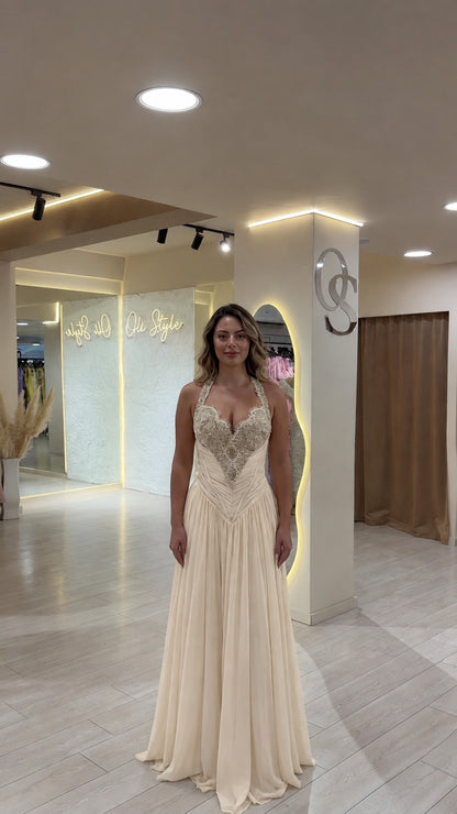 Model wearing champagne cream halter evening gown with beaded detail